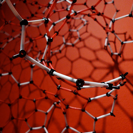Detail of hyperbolic model made of small sticks on red background.