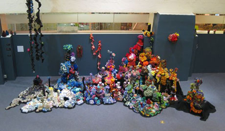 Installation view of crochet coral reef sculptures in large gallery space.