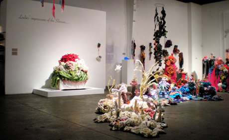 Installation view of crochet coral reef sculptures in gallery space.