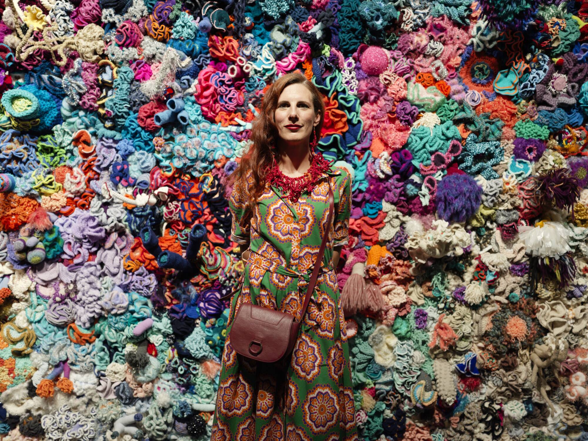 woman standing in front of a wall of crocheted corals