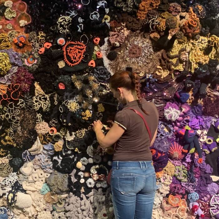 woman installing crochet coral reef artwork